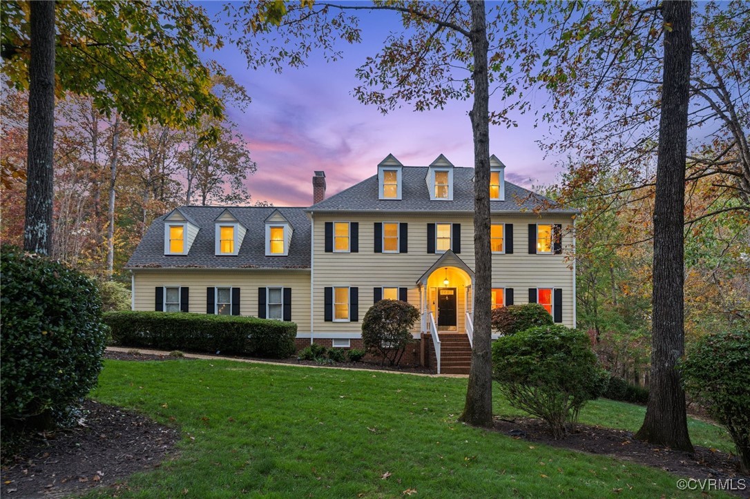 a front view of a house with garden and trees