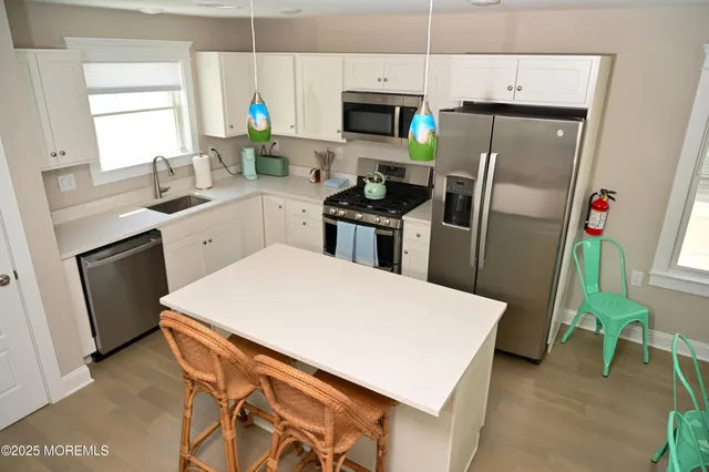a kitchen with stainless steel appliances a refrigerator sink and white cabinets
