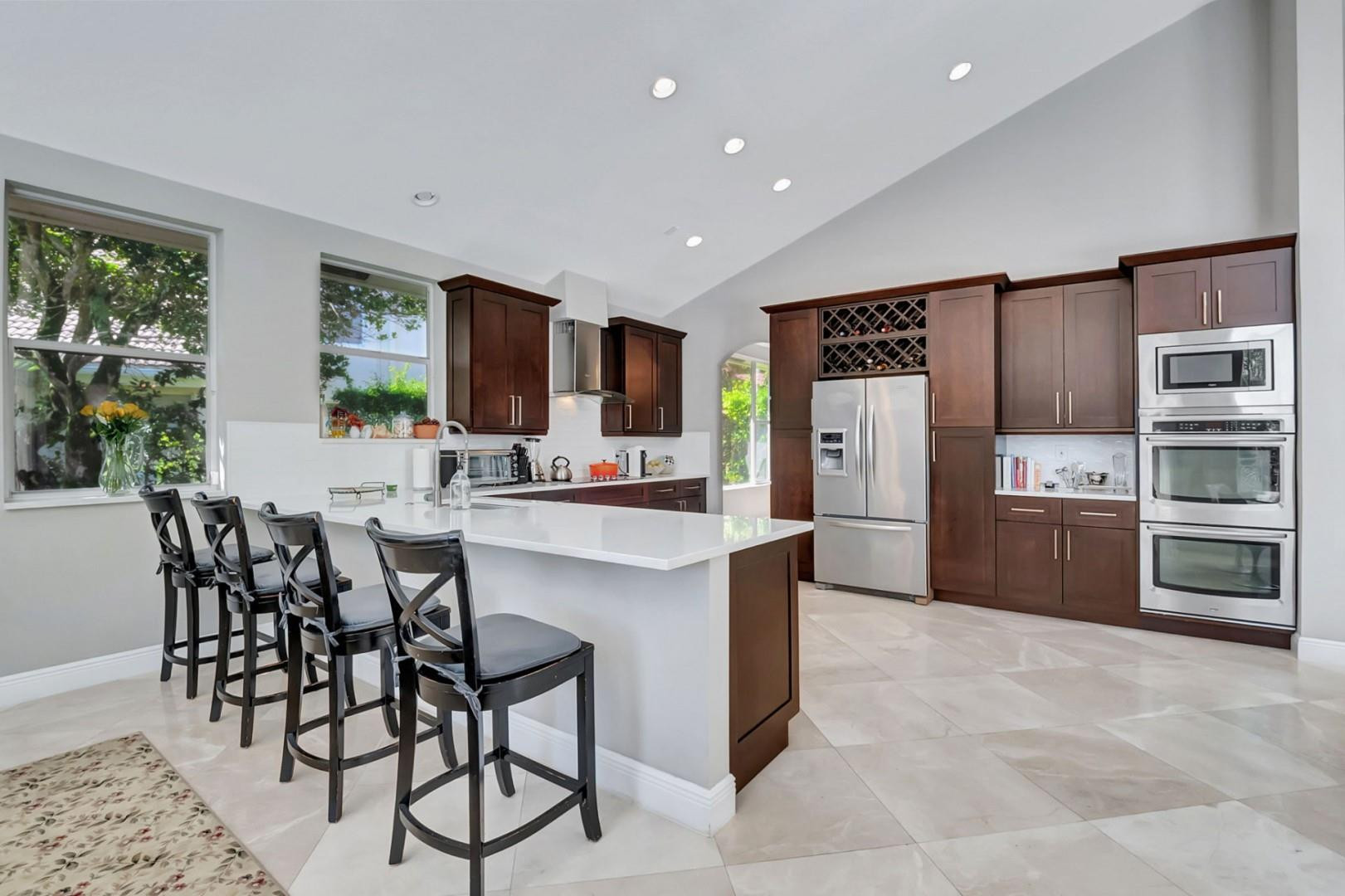 6096 Northwest 30th Way Boca Raton, FL 33496 - Photo 7 of 24 a kitchen with stainless steel appliances kitchen island granite countertop a refrigerator and a stove top oven