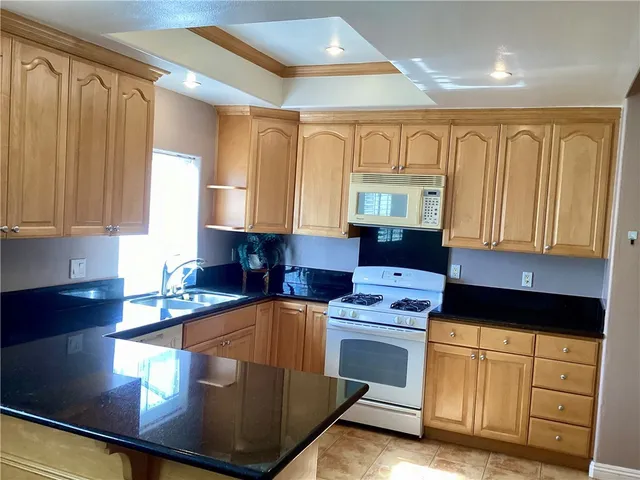 a kitchen with granite countertop wooden cabinets a sink and a stove