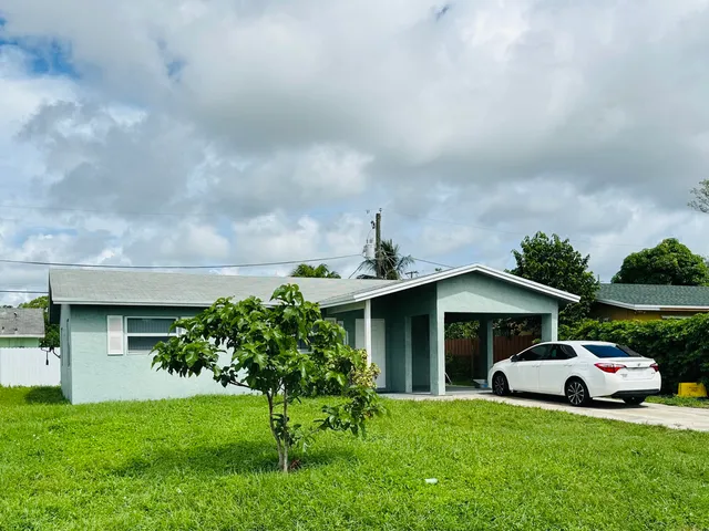 a front view of a house with a garden and trees