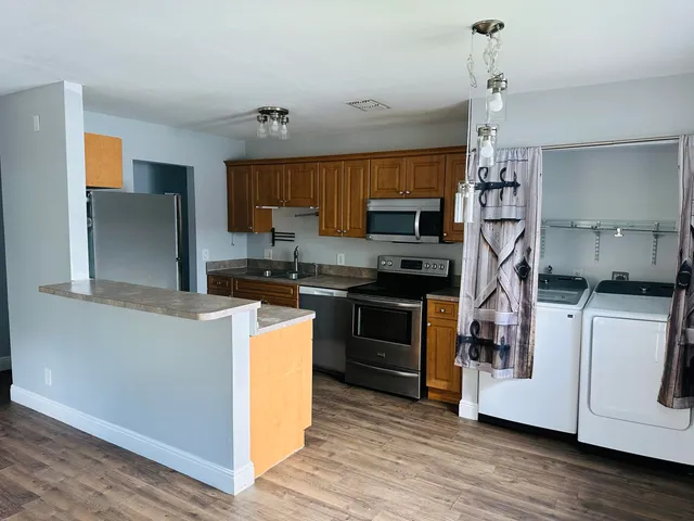 a kitchen with kitchen island stainless steel appliances a stove cabinets and wooden floor