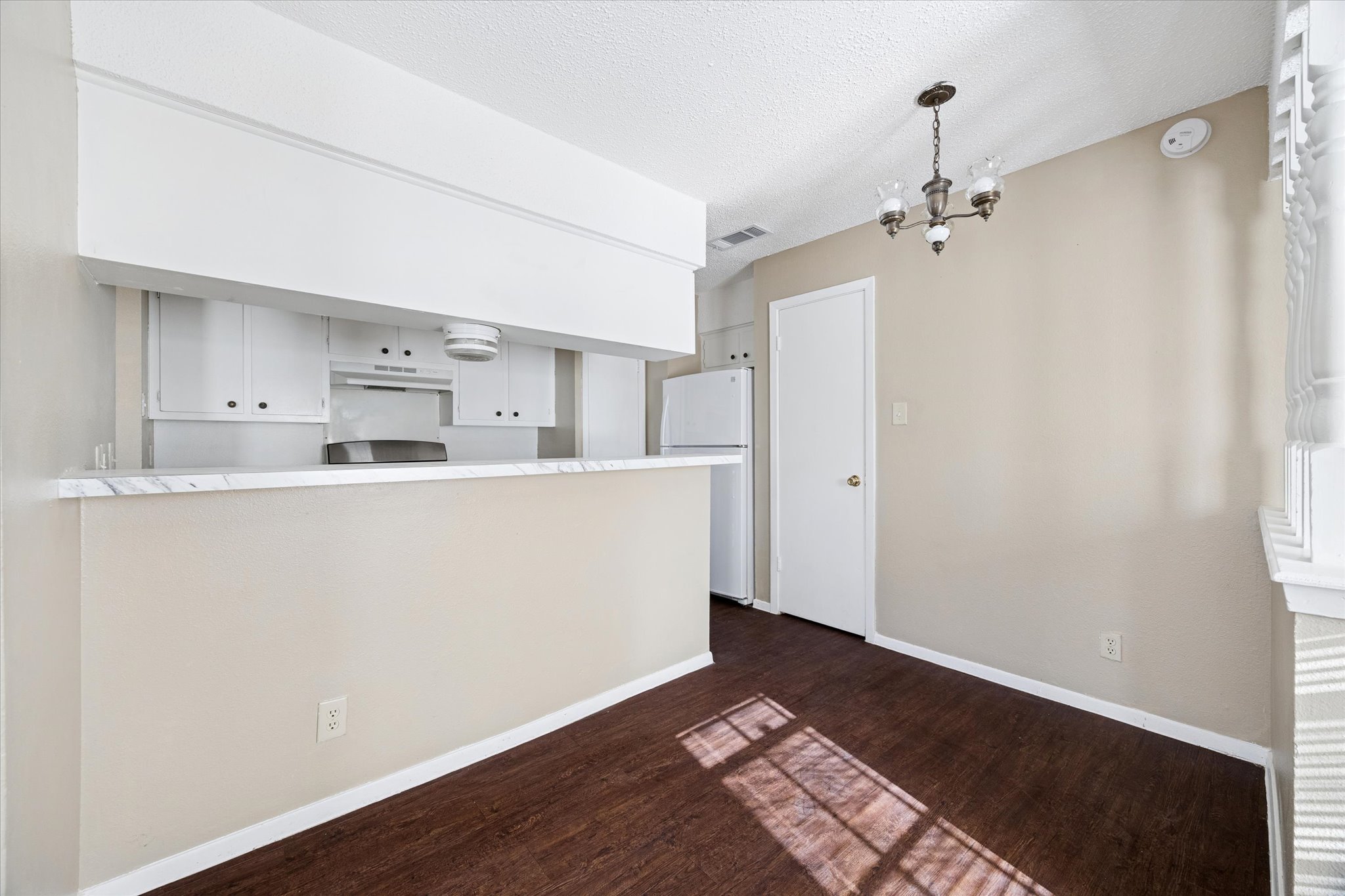 908 Kirschner Place, Unit B Austin, TX 78758 - Photo 5 of 10 Kitchen with a chandelier, white cabinetry, freestanding refrigerator, a textured ceiling, and light countertops