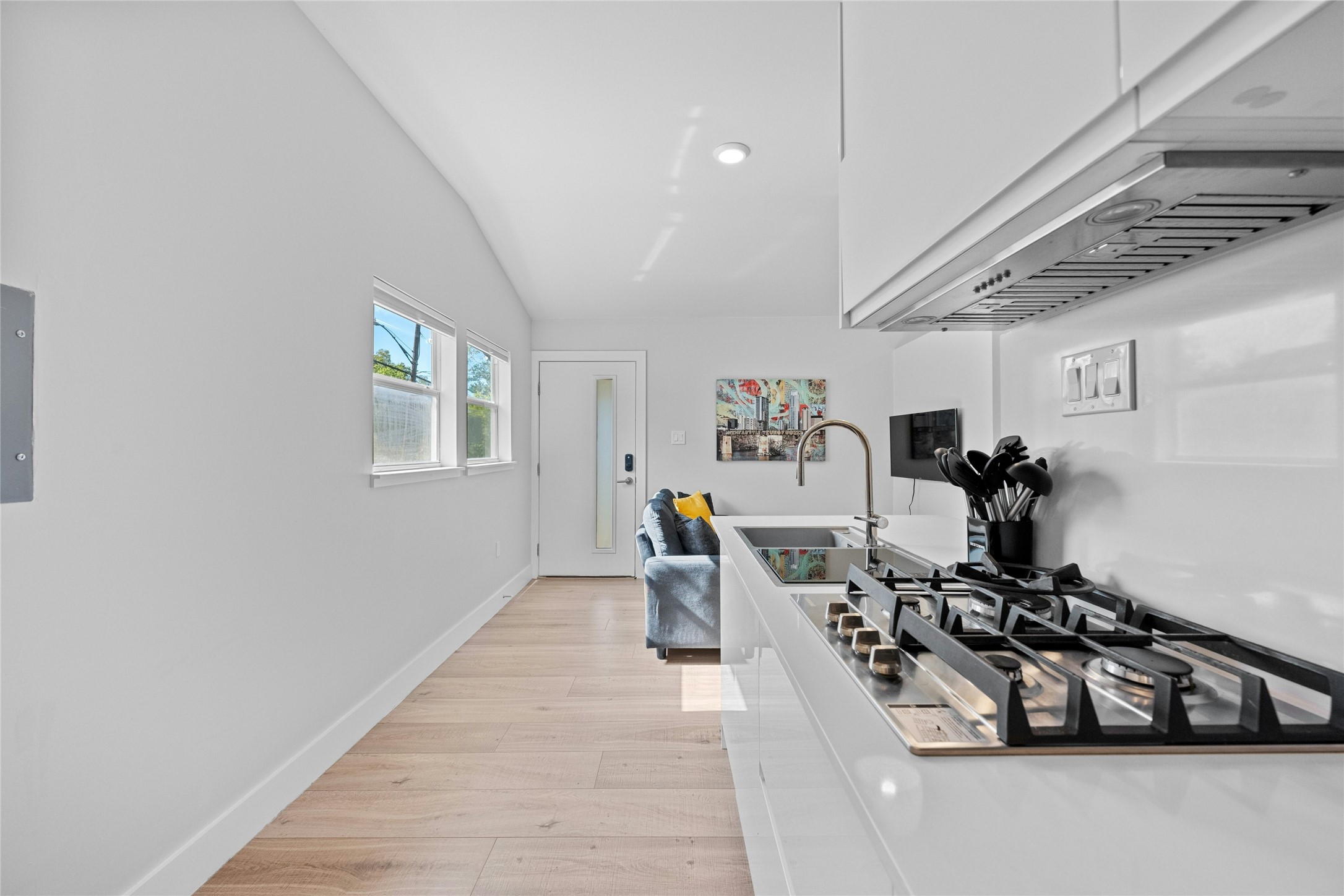 2201 Leon Street, Unit D Austin, TX 78705 - Photo 13 of 24 Kitchen with lofted ceiling, extractor fan, white cabinetry, sink, and stainless steel gas cooktop
