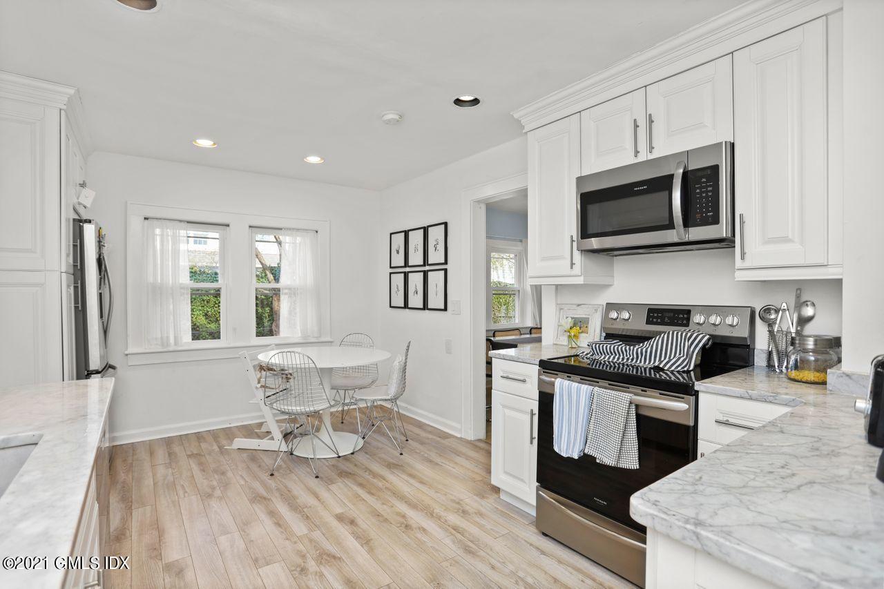 55 Oval Avenue Riverside, CT 06878 - Photo 11 of 29 a kitchen with stainless steel appliances granite countertop a stove top oven a sink a dining table and chairs with wooden floor