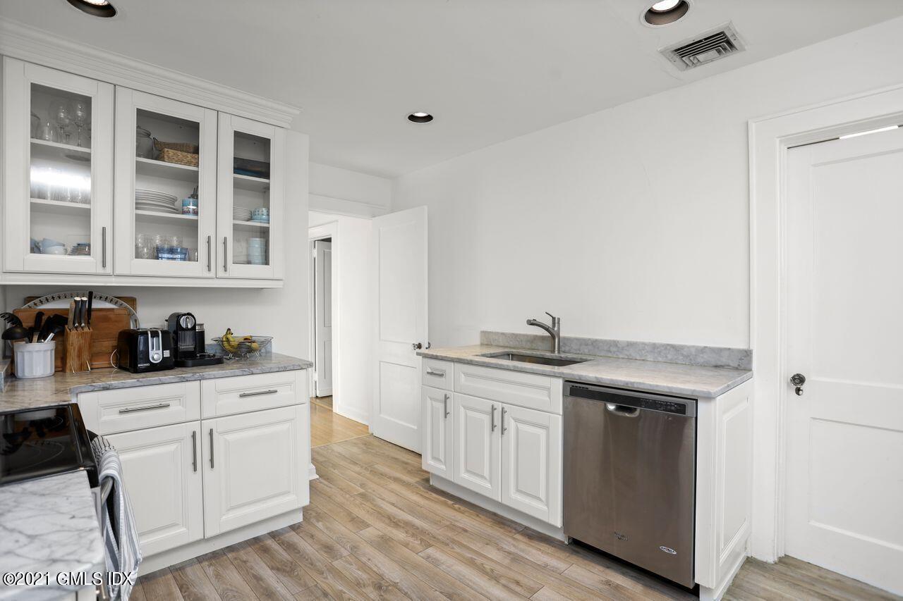 55 Oval Avenue Riverside, CT 06878 - Photo 12 of 29 a kitchen with stainless steel appliances granite countertop a stove a sink dishwasher and white cabinets with wooden floor