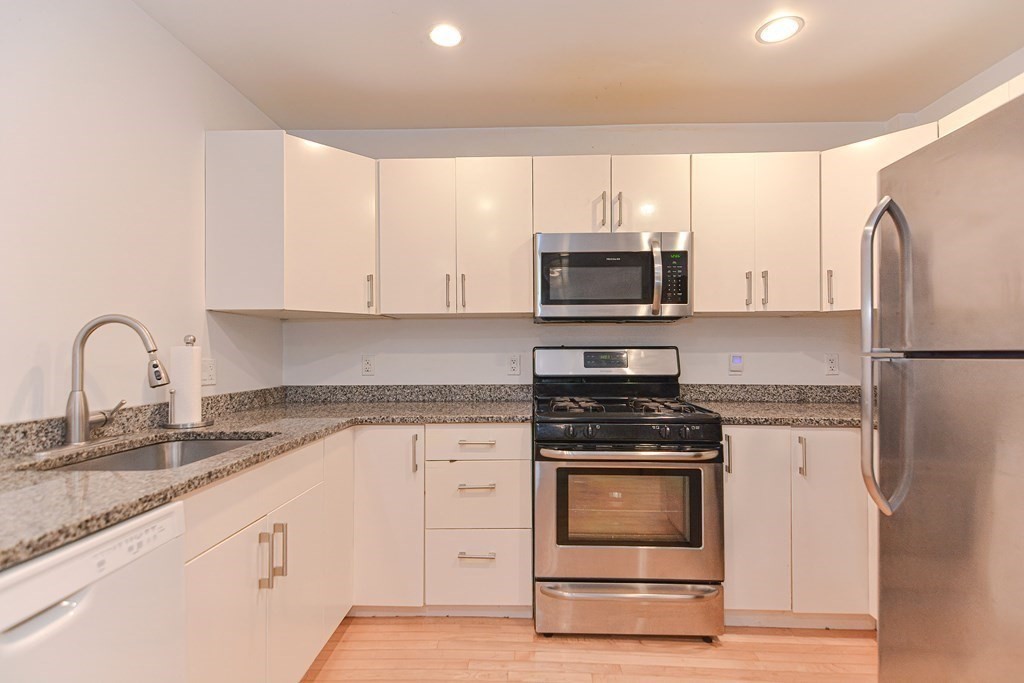 89 Broad Street, Unit 1 Lynn, MA 01902 - Photo 2 of 23 a kitchen with granite countertop white cabinets and stainless steel appliances