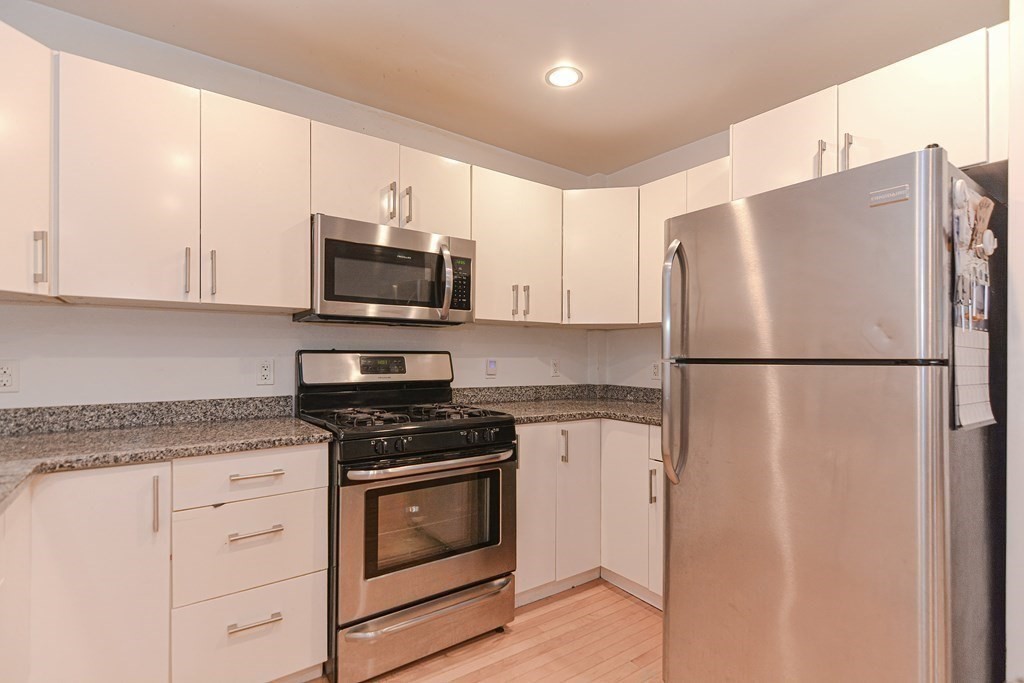 89 Broad Street, Unit 1 Lynn, MA 01902 - Photo 3 of 23 a kitchen with stainless steel appliances white cabinets and a refrigerator