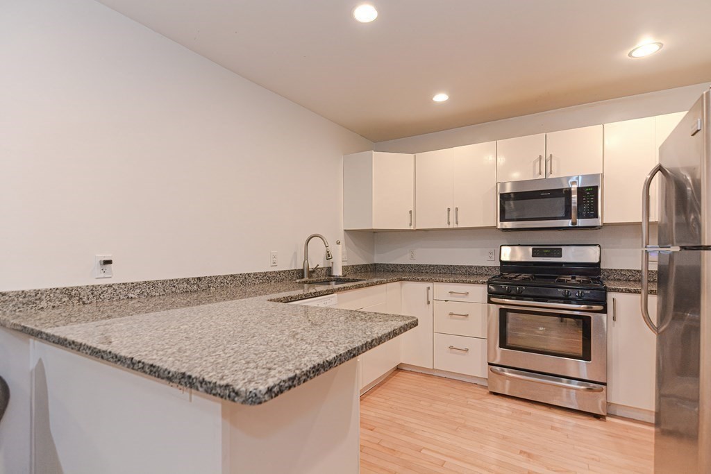 89 Broad Street, Unit 1 Lynn, MA 01902 - Photo 4 of 23 a kitchen with granite countertop a sink and steel appliances
