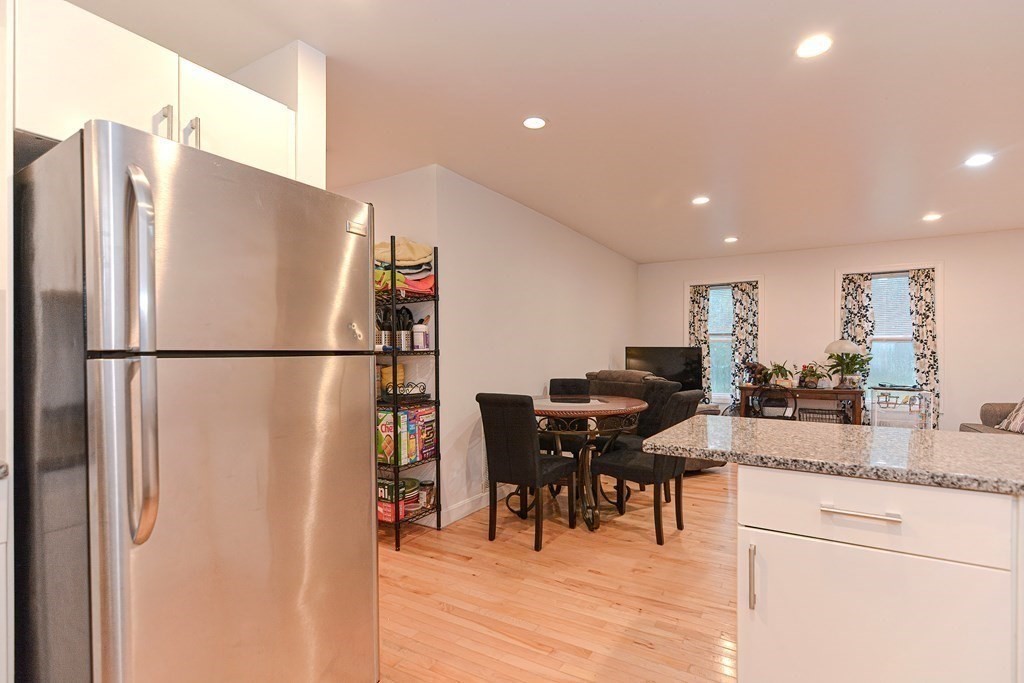 89 Broad Street, Unit 1 Lynn, MA 01902 - Photo 6 of 23 a kitchen with stainless steel appliances granite countertop refrigerator sink dining table and chairs