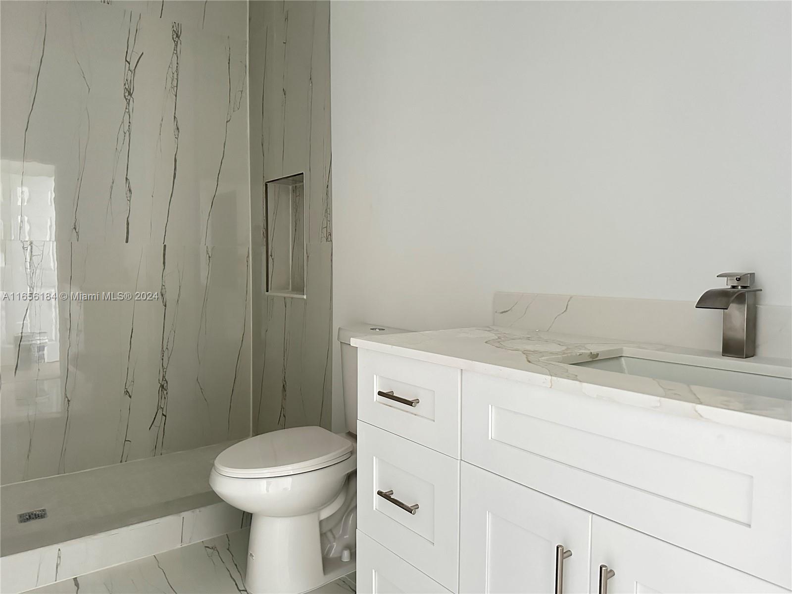 2933 Northwest 57th Street, Unit 2933 Miami, FL 33142 - Photo 11 of 14 a bathroom with a granite countertop toilet a sink and shower