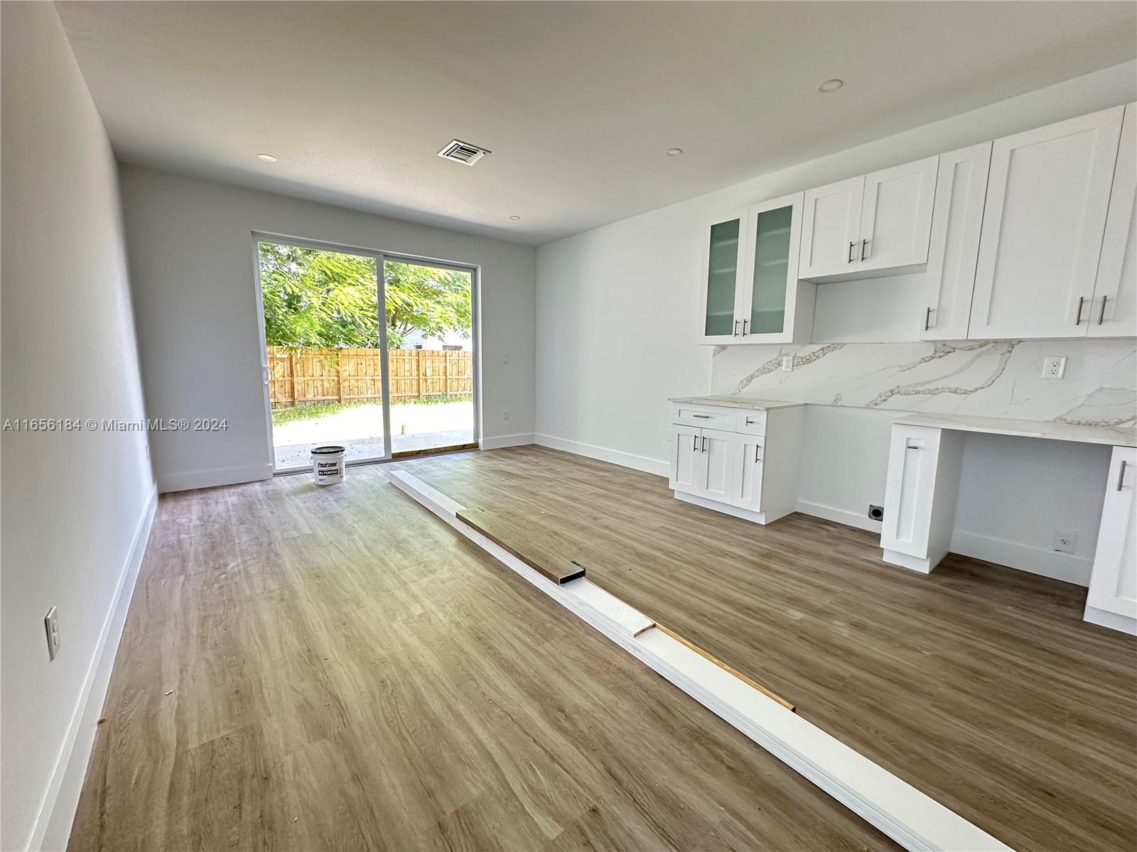 2933 Northwest 57th Street, Unit 2933 Miami, FL 33142 - Photo 2 of 14 a view of an empty room and window and kitchen with wooden floor