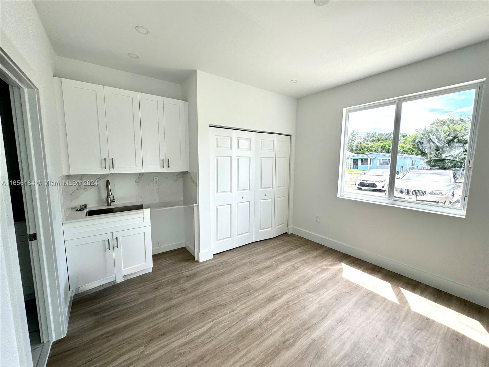 2933 Northwest 57th Street, Unit 2933 Miami, FL 33142 - Photo 4 of 14 a kitchen with wooden floors and white cabinets