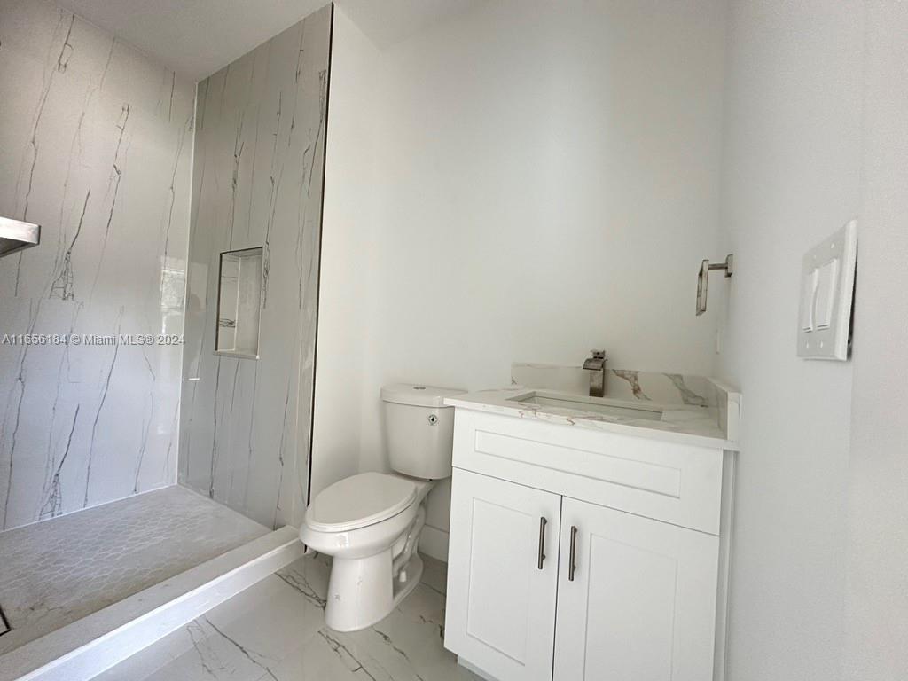 2933 Northwest 57th Street, Unit 2933 Miami, FL 33142 - Photo 5 of 14 a bathroom with a granite countertop toilet a sink and a mirror