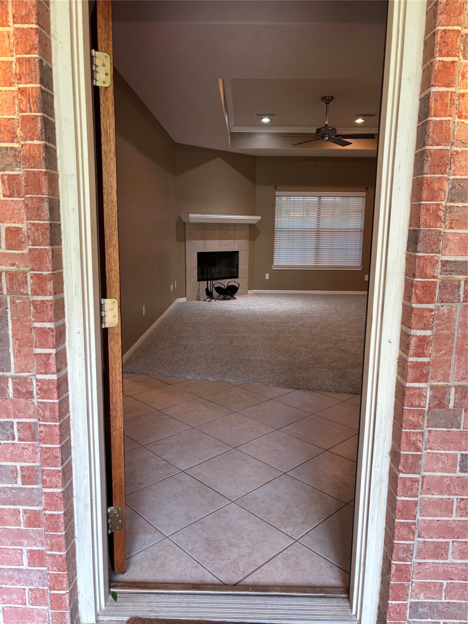 3238 Glenforest Road Montgomery, TX 77356 - Photo 3 of 41 The entrance to a cozy living room with a tiled entryway leading to carpeted flooring. It features a ceiling fan, recessed lighting, a large window, and a corner fireplace with a mantel.