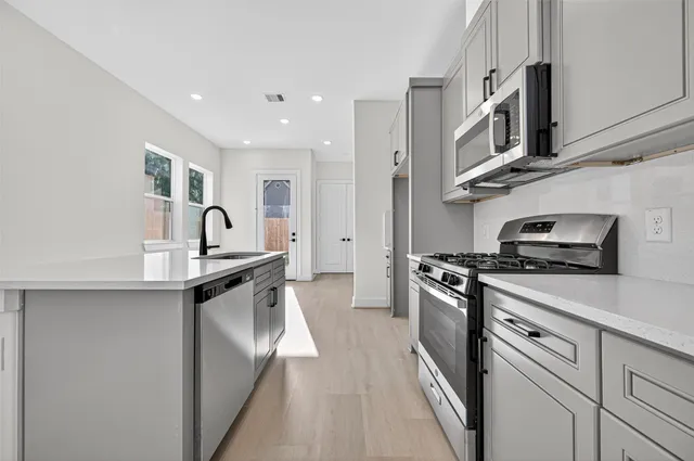 a kitchen with stainless steel appliances granite countertop a sink and a stove