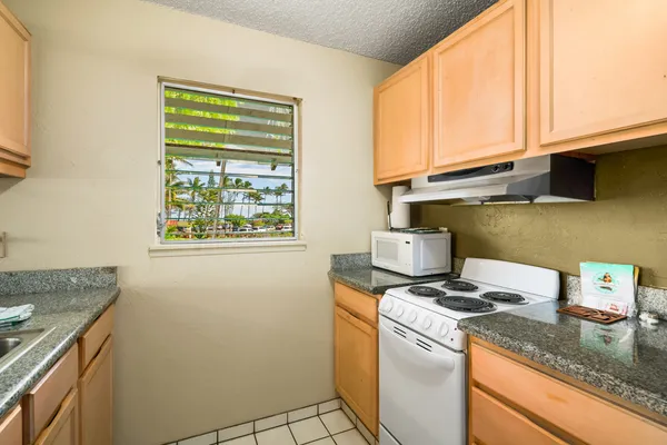 a kitchen with granite countertop cabinets appliances and a window