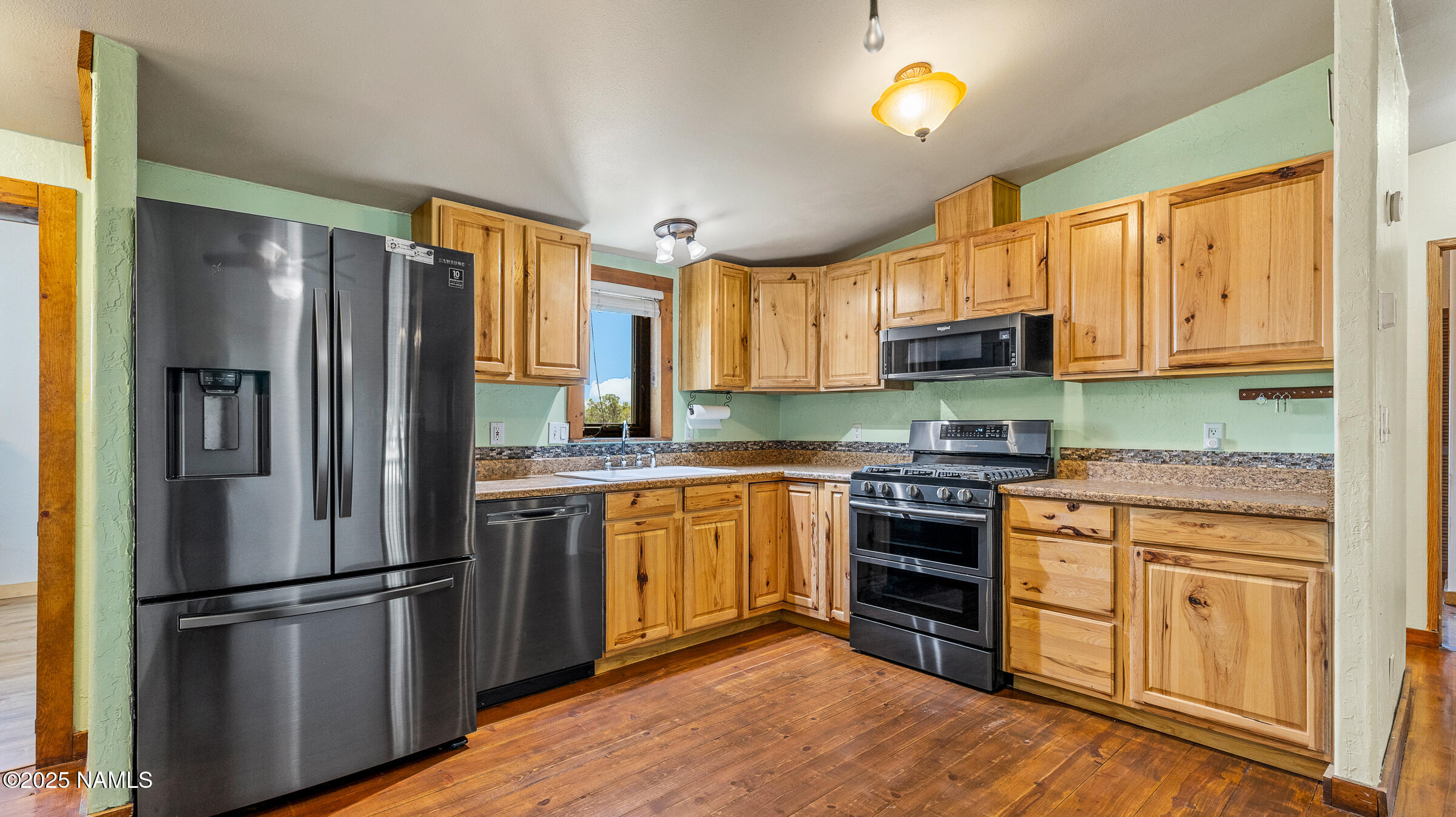 10350 Ghost Rider Trail Flagstaff, AZ 86004 - Photo 8 of 39 a kitchen with stainless steel appliances granite countertop a refrigerator a stove top oven a sink and dishwasher with wooden floor