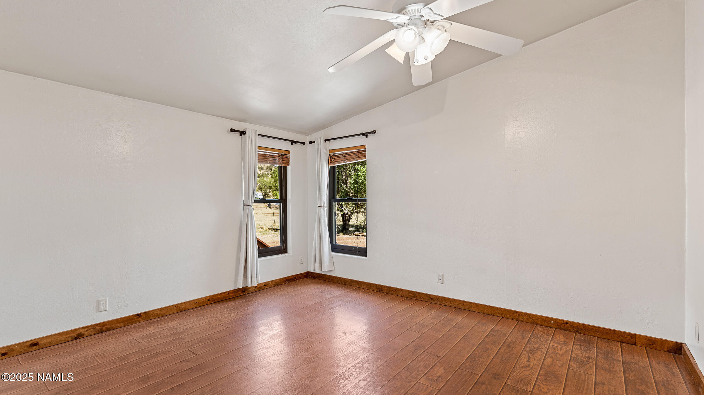 10350 Ghost Rider Trail Flagstaff, AZ 86004 - Photo 9 of 39 an empty room with wooden floor chandelier fan and windows