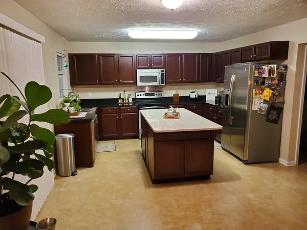 a kitchen with stainless steel appliances granite countertop a refrigerator a stove and a sink