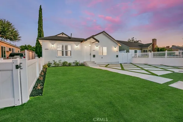 a front view of a house with a yard and trees