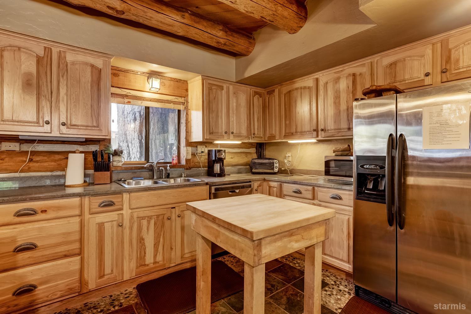 3140 Sacramento Avenue South Lake Tahoe, CA 96150 - Photo 9 of 30 a kitchen with a sink a kitchen island wooden cabinetry and stainless steel appliances