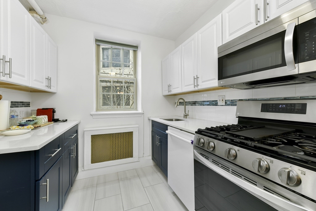 1490 Beacon Street, Unit 1A Brookline, MA 02446 - Photo 2 of 15 a kitchen with stainless steel appliances a sink dishwasher stove and oven with cabinets