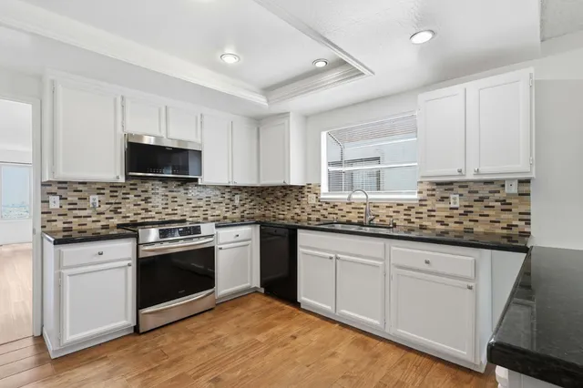a kitchen with granite countertop a stove sink and cabinets