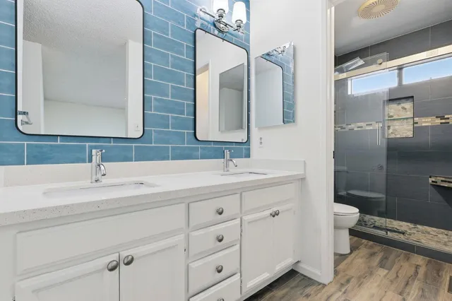 a bathroom with a double vanity sink toilet and mirror