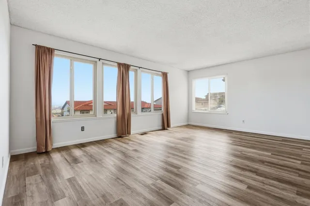 a view of an empty room with a window and wooden floor