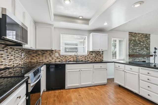 a kitchen with granite countertop white cabinets and sink