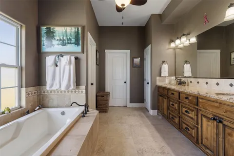 a bathroom with a tub a double vanity sink and a large mirror