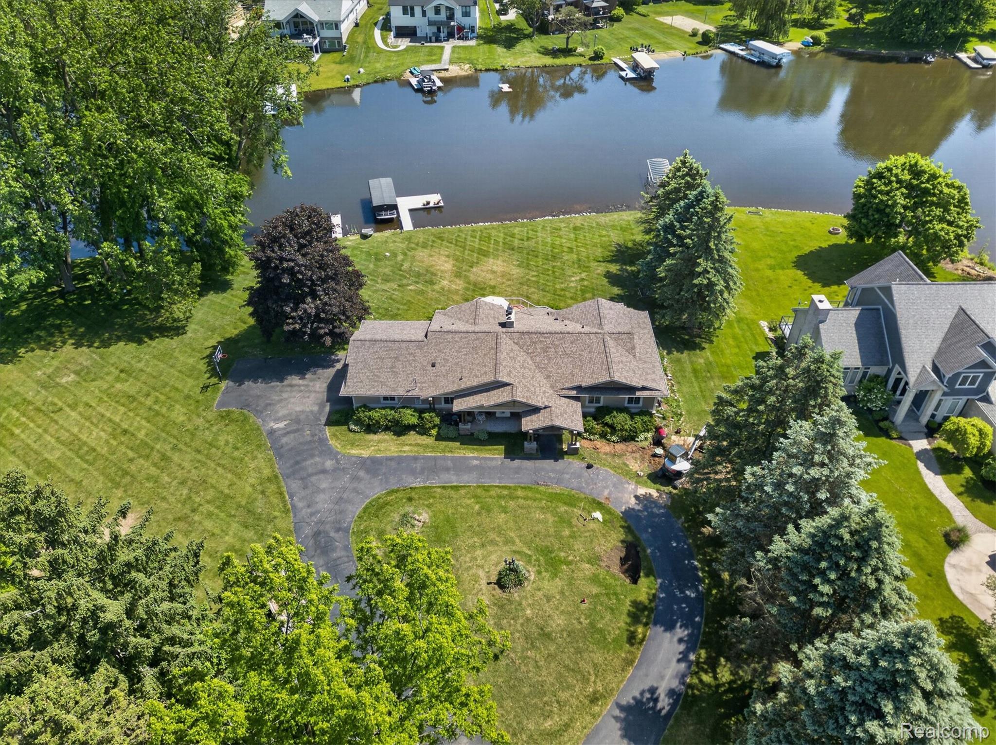3860 East Commerce Road Commerce Township, MI 48382 - Photo 52 of 72 Waterfront property featuring a private dock, expansive green lawn, mature trees, and a paved circular driveway