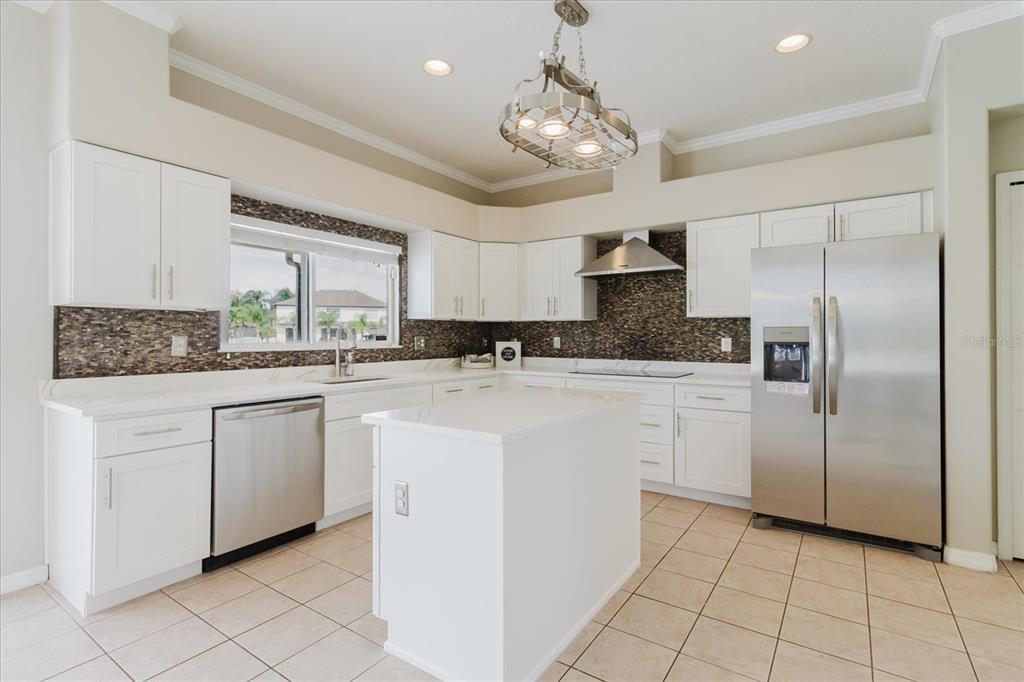 1725 Pink Guara Court Trinity, FL 34655 - Photo 33 of 100 a kitchen with kitchen island granite countertop a refrigerator a oven a sink a stove and white cabinets