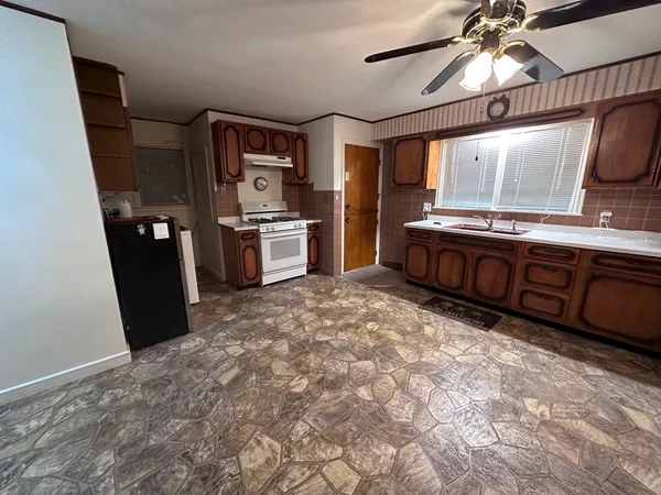 a large kitchen with stainless steel appliances a sink a stove a refrigerator cabinets and a large window