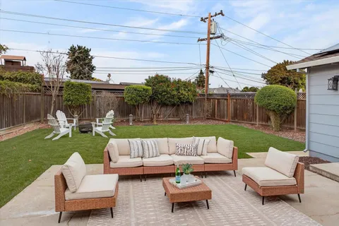 a view of a patio with couches chairs and a yard with wooden fence
