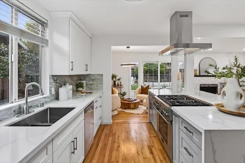 a kitchen with stainless steel appliances granite countertop sink stove and white cabinets