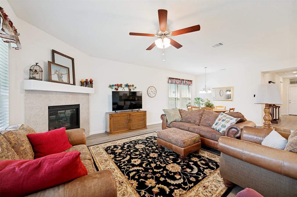 413 Wiggins Way Van Alstyne, TX 75495 - Photo 11 of 25 Living room featuring wood-finish flooring, a ceiling fan with light fixture, and a fireplace with a mantel