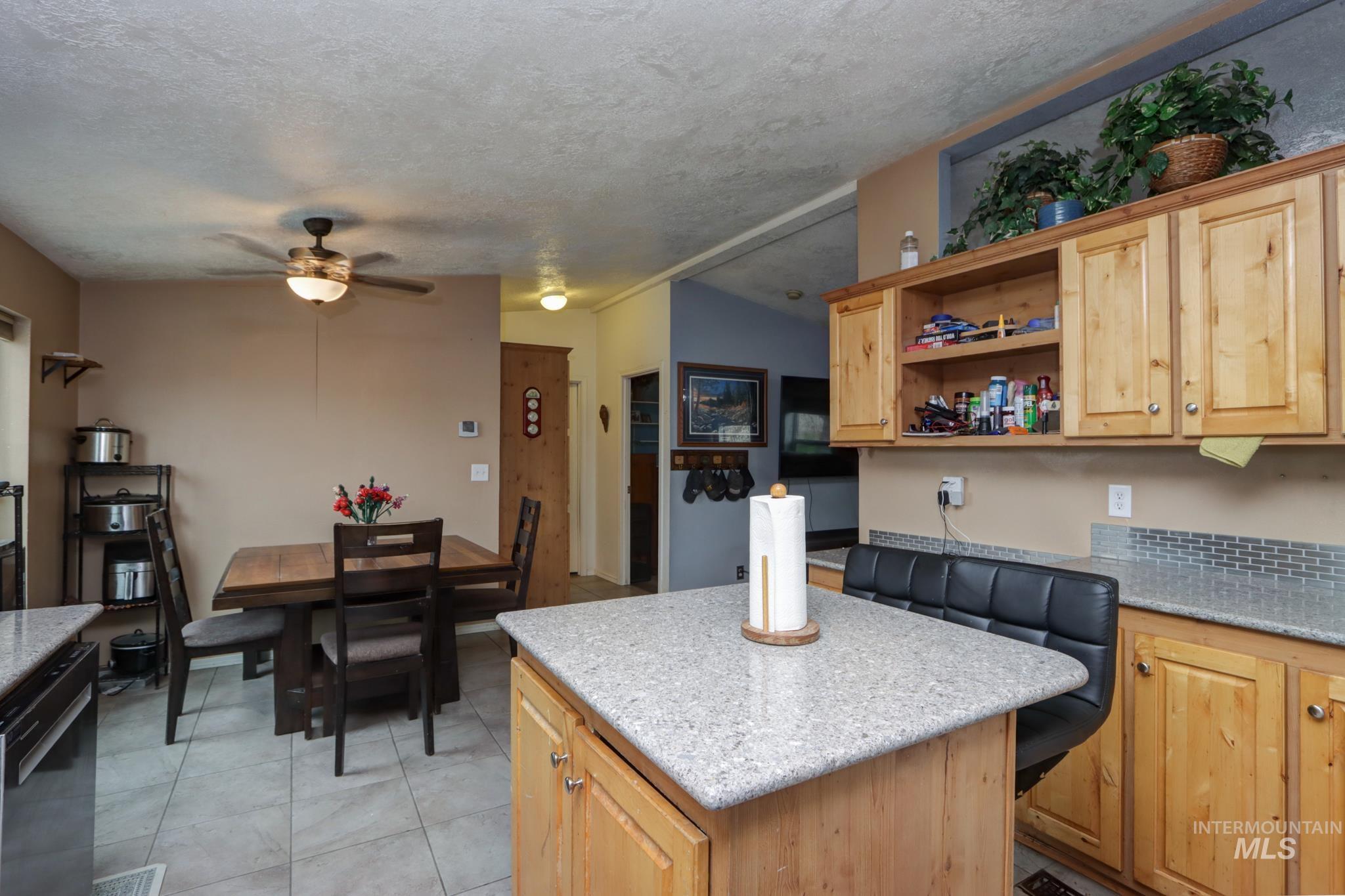 1583 Dustin Lane Vale, OR 97918 - Photo 2 of 39 Kitchen with a center island, light wood finish cabinetry, black dishwasher, a ceiling fan, and light tile patterned flooring