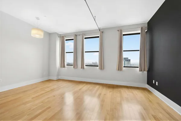 a view of empty room with wooden floor and fan