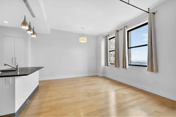 a view of an empty room with window and wooden floor