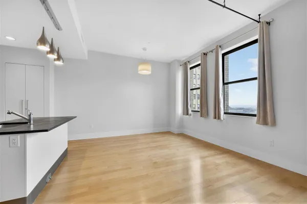 a view of an empty room with window and wooden floor