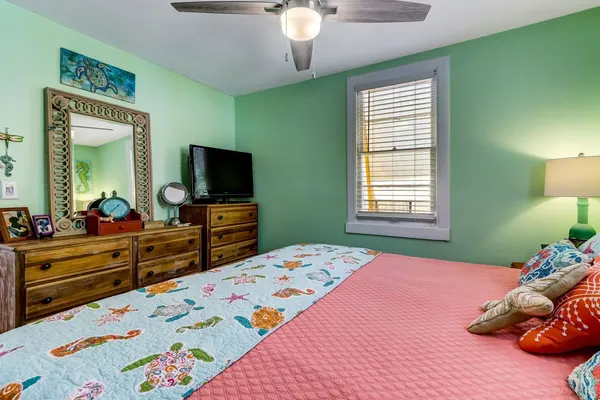 a bedroom with a bed and a flat tv screen on dresser
