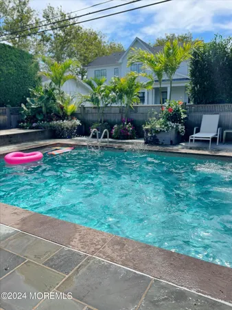 a view of backyard with swimming pool and seating space