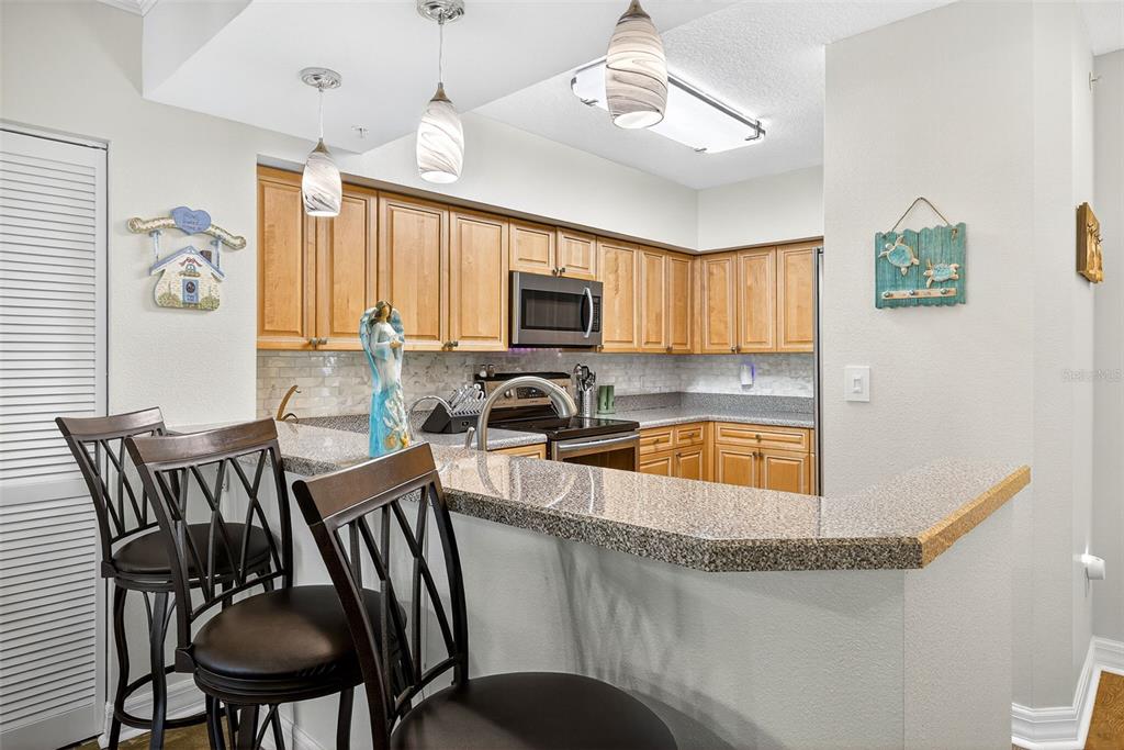 4516 Seagull Drive, Unit 519 New Port Richey, FL 34652 - Photo 13 of 54 a kitchen with granite countertop a dining table chairs microwave and sink