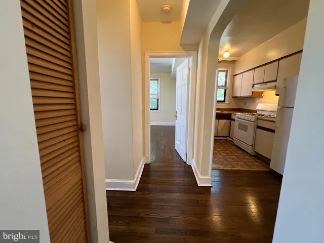 a view of a hallway with wooden floor cabinets and a kitchen