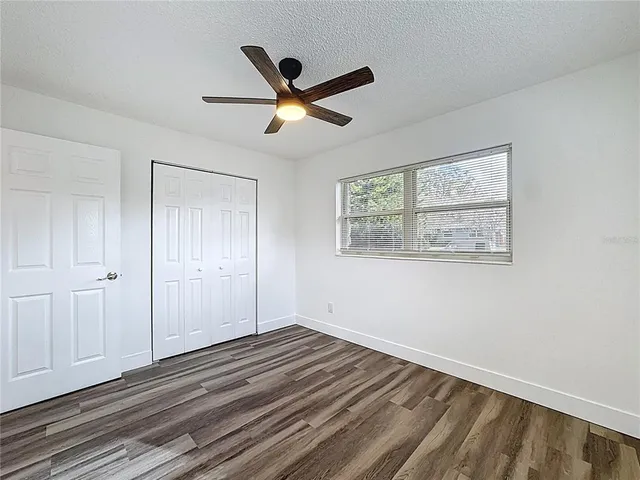a view of empty room with wooden floor and fan