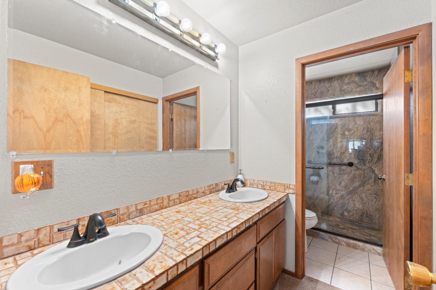 14800 McElroy Road Auburn, CA 95602 - Photo 17 of 39 a bathroom with a granite countertop sink a mirror and a shower