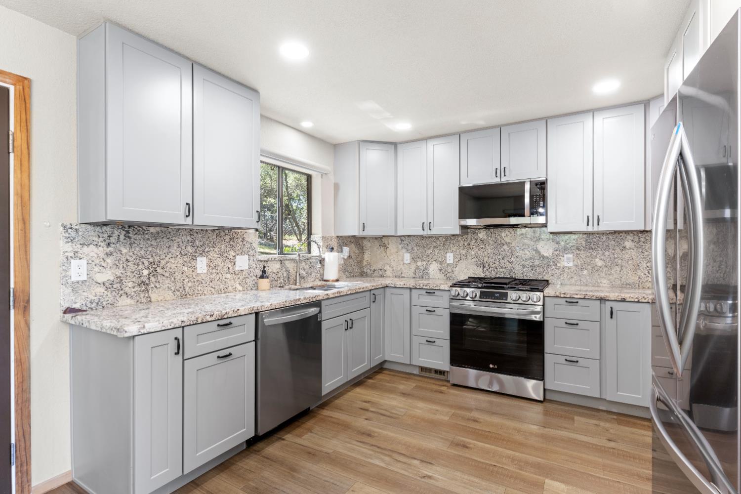 14800 McElroy Road Auburn, CA 95602 - Photo 3 of 39 a kitchen with stainless steel appliances granite countertop a stove top oven a sink and dishwasher a refrigerator with wooden floor