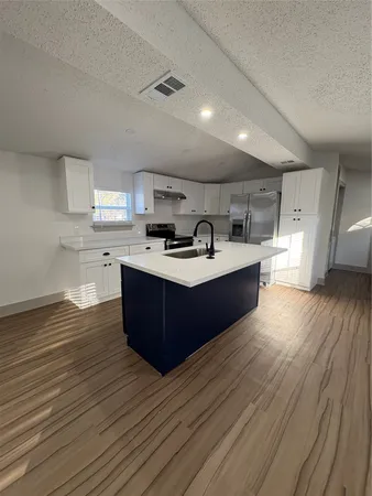 a large kitchen with stainless steel appliances a large counter top a stove a sink and a refrigerator